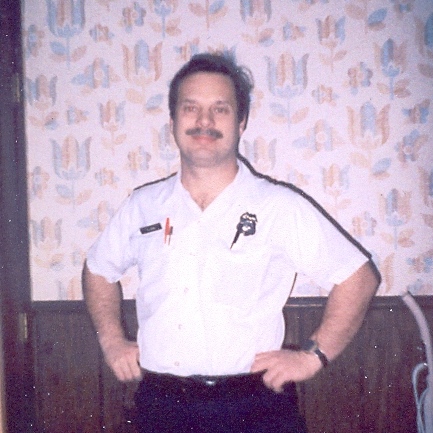 Charles wearing a white uniform shirt and badge of the City of Columbus the Division of Fire Auxiliary which he was a member from 1976 to 1980.