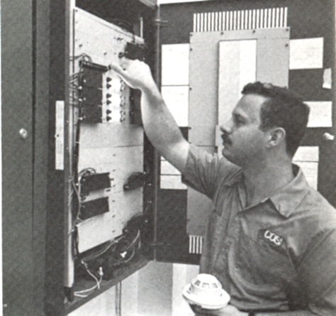 Charles Legg adjusting controls at the COSI fire alarm control panel.
