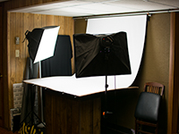 A small photography studio with soft box lights on either side of a white backdrop used for photographing items for sale on eBay.